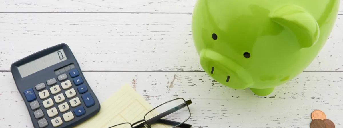 Calculator, coins and a piggy bank on a desk